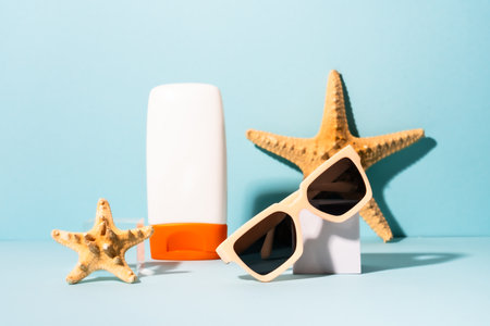 Summer holidays concept. Sunglasses, sunscreen and sea shell with sunny shadows.