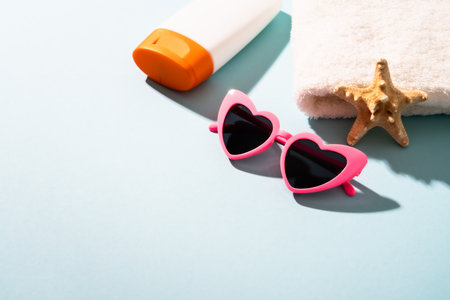 Summer holidays concept. Sunglasses, sunscreen and sea shell with sunny shadows.