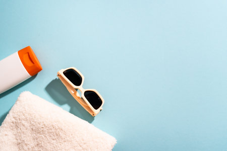 Summer flat lay background. Sunglasses, sunscreen and sea shell with sunny shadows.