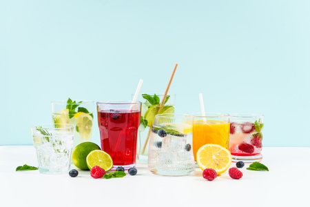 Summer drinks, colored cocktails on white background. Lemonade, mojito, raspberry lemonade, tonic water with fresh fruits and berries.の写真素材