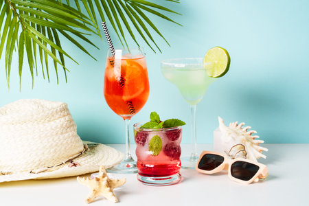 Summer alcohol Cocktail party. Margarita, raspberry mojito with summer accessories at blue background.の写真素材