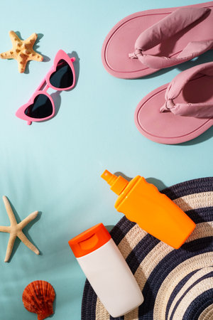 Beach cloth and accossories with sea shells on blue background. Top view with hard shadows.