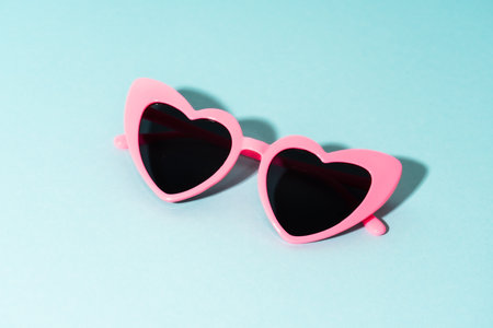 Heart-shaped glasses on a colored background. Sun shadows.の写真素材