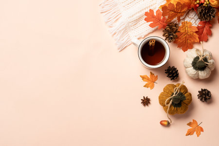 Autumn background. Hot tea, knitted scarf and fallen leaves on color background. Top view with copy...