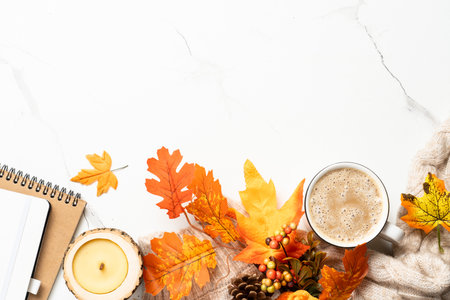 Autumn workspace on white background. Notebook, mug of coffee, cozy sweater and yellow leaves. Flat...