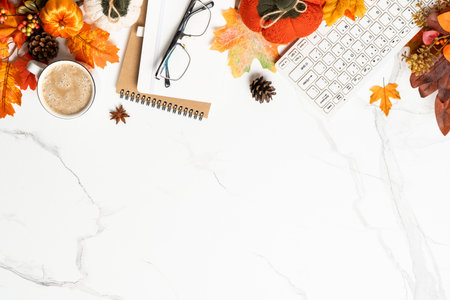 Autumn office desk. Laptop, notebook, cup of coffee and yellow leaves with pumpkins. Flat lay with...