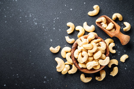 Cashew nuts in bowl at black background. Flat lay with space for text.の写真素材