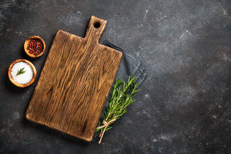 Cutting board, spices and herbs at black background. Flat lay with space for text.の写真素材