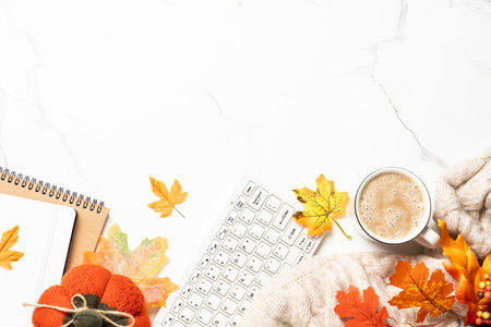 Autumn office desk. Laptop, notebook, cup of coffee and yellow leaves with pumpkins. Flat lay with...
