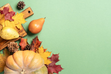 Autumn flat lay background. Pumpkin, fruits, spikelets and fallen leaves on color background.の写真素材