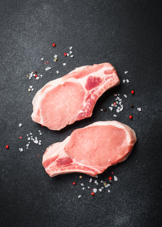 Raw pork meat steaks on black background. Flat lay with copy space.の写真素材
