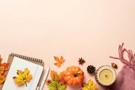 Autumn flat lay background. Autumn leaves, notepad, scarf, candle and spices on yellow background.