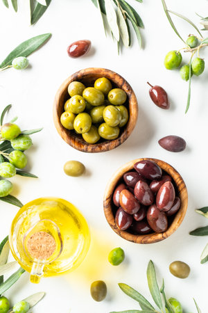 Olives in wooden bowls and Olive oil in the bottle at white table with copy space.の写真素材