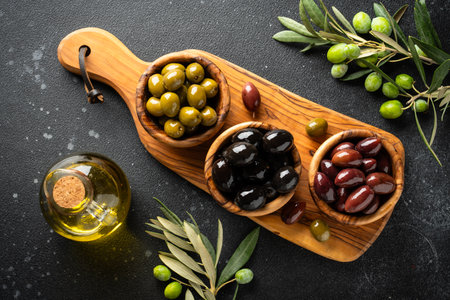 Olives mix and Olive oil with fresh olive tree branches. Top view on black table.の写真素材