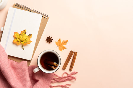 Autumn flat lay background. Notebook, hot tea and scarf with fallen leaves.