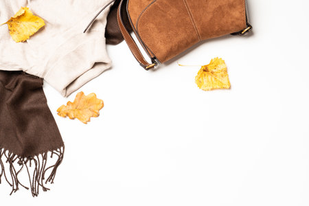 Autumn flat lay background. Woman cloth and beauty products on white with fallen leaves.の写真素材