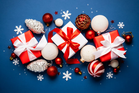 Christmas flat lay on blue background. Christmas presents, red and white decorations. Holiday...