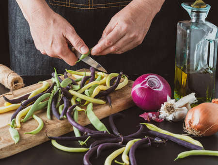 Woman is cleaning green beans in the kitchen.