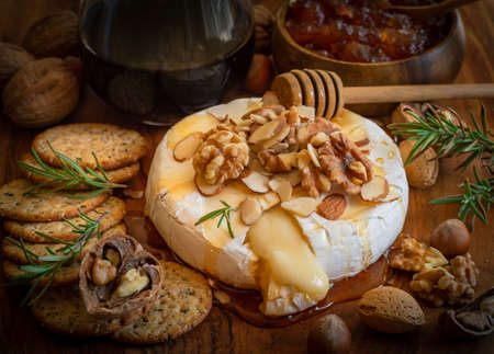 Cheese board served for an appetizer: baked brie,crackers,jam and nuts.の写真素材