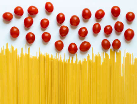 Dry pasta and red cherry tomatoe on a white background.の写真素材
