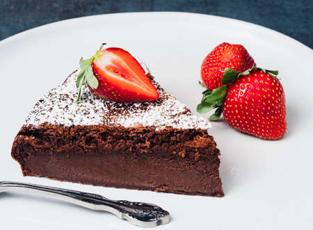Piece of chocolate custard cake garnished with fresh strawberries.