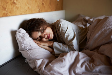 Photo of sleeping young woman lies in bed with eyes closedの写真素材
