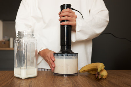 Woman preparing milkshake with blender at the kitchenの写真素材