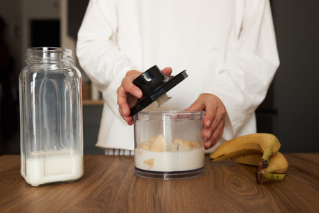 Woman preparing milkshake with blender at the kitchenの写真素材