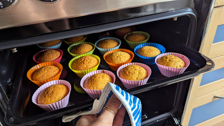 Freshly baked homemade cupcakes in colorful silicone molds inside ovenの写真素材