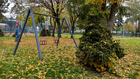 Autumn Childrens Playground with Swings and Trees in City Parkの写真素材