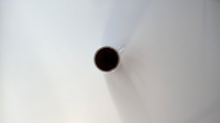 Minimalist black coffee cup on white table expressing calm solitudeの写真素材
