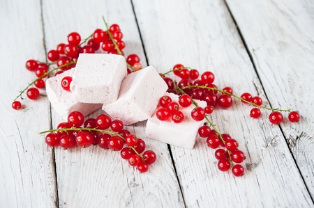 marshmallows with raspberry and red currant on a white wooden tableの写真素材