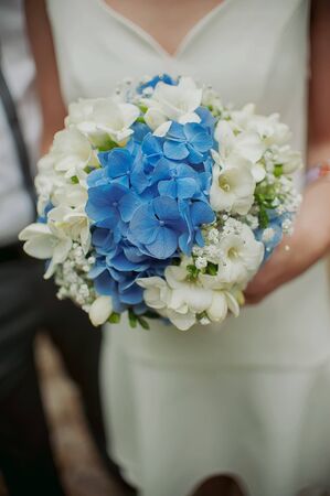 beautiful wedding bouquet of flowers in the hands of the brideの写真素材