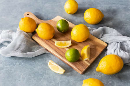Fresh lemons and limes scattered on chalkboard, background, textileの写真素材