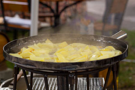 Young appetizing potatoes fried in a pan outside. Food court.の写真素材