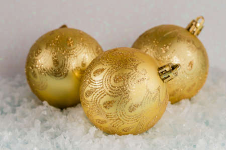 Golden Christmas balls lie on the snow, white background, front viewの写真素材