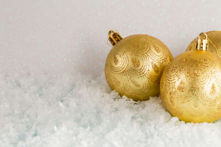 Golden Christmas balls lie on the snow, white background, front view, copy spaceの写真素材