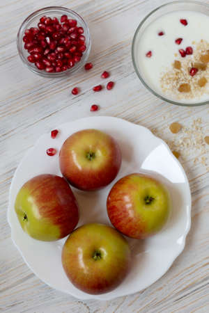 Breakfast of yogurt, apples, pomegranate, muesli with raisins on a light background, flat layの写真素材