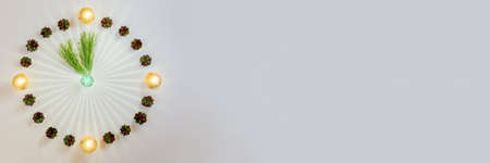 Original new year clock made of balls and cones, pine branches instead of arrows, banner, flat lay, copy space, light backgroundの写真素材