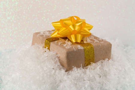 Gift box with a big beautiful yellow bow in the snow, front view, copy spaceの写真素材