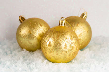 Three Golden Christmas balls lie on the snow, white background, front viewの写真素材