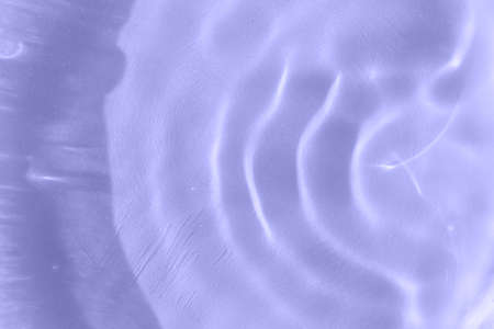 Sunbeams in stripes on the water. Close-up of defocused waves texture. Color of the Year 2022 Veri Periの写真素材