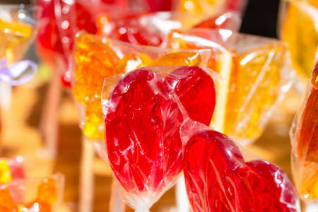Heart shaped lollipops in packaging close up, red and yellow. Front viewの写真素材