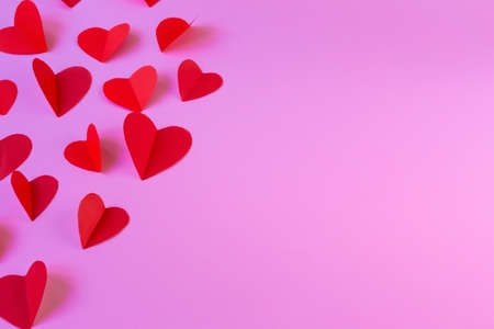 Flying red hearts on a pink background. Valentines Day. The perfect solution for your design on the theme of love. Top view, copy spaceの写真素材