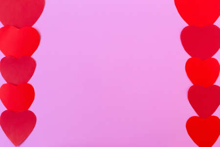 Framing a pink background on the sides with ornamentof red hearts is the perfect solution for your design. Valentines Day. Flat lay, copy space, selective focusの写真素材