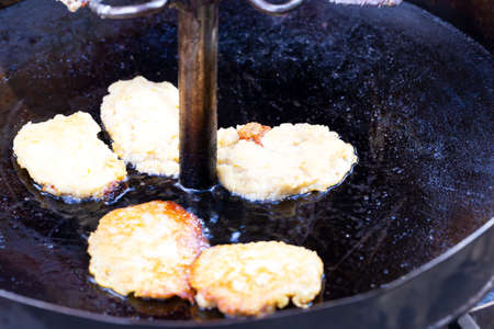 Fresh yummy potato fritters are fried in a large frying pan. Top view, copy space, space for text