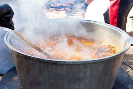 A chef cooks bograch soup in a large vat outside. Food court. Fresh and appetizing