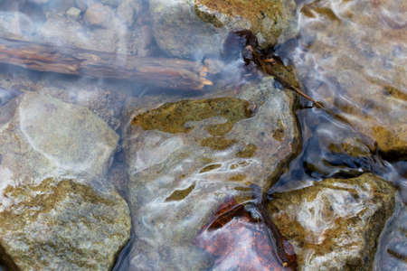 A mountain brook flows quietly among the stones. A natural backdrop. Selective focus