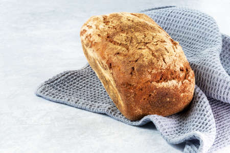 Loaf of freshly baked dark Lithuanian bread on a napkin on a light background. Top view. Close up