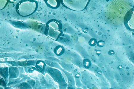 Yellow oil stains on wavy water, circles in the water on a light blue background, beauty in plain, a...